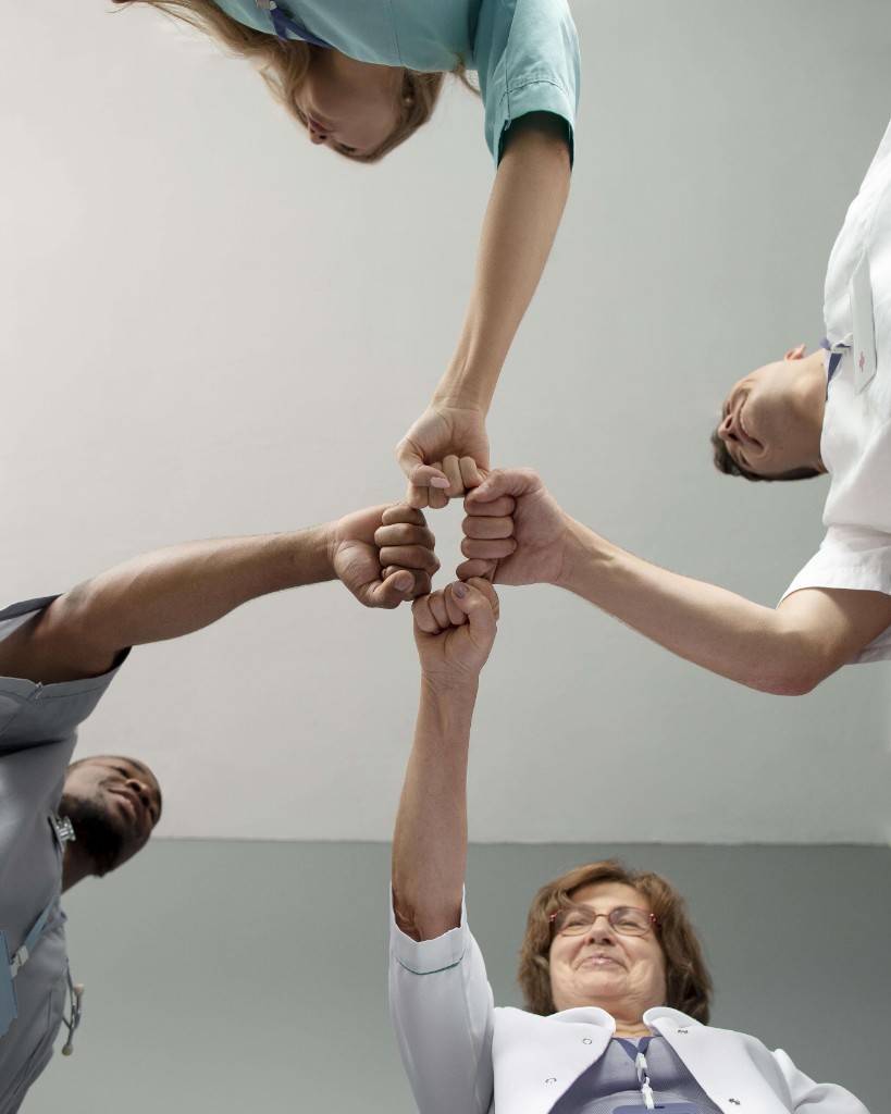 Healthcare team members joining hands in collaboration
